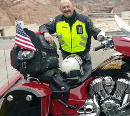 A man in yellow jacket standing next to motorcycle.