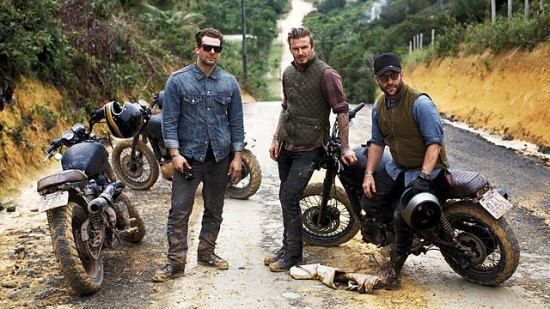 Three men standing next to motorcycles on a dirt road.